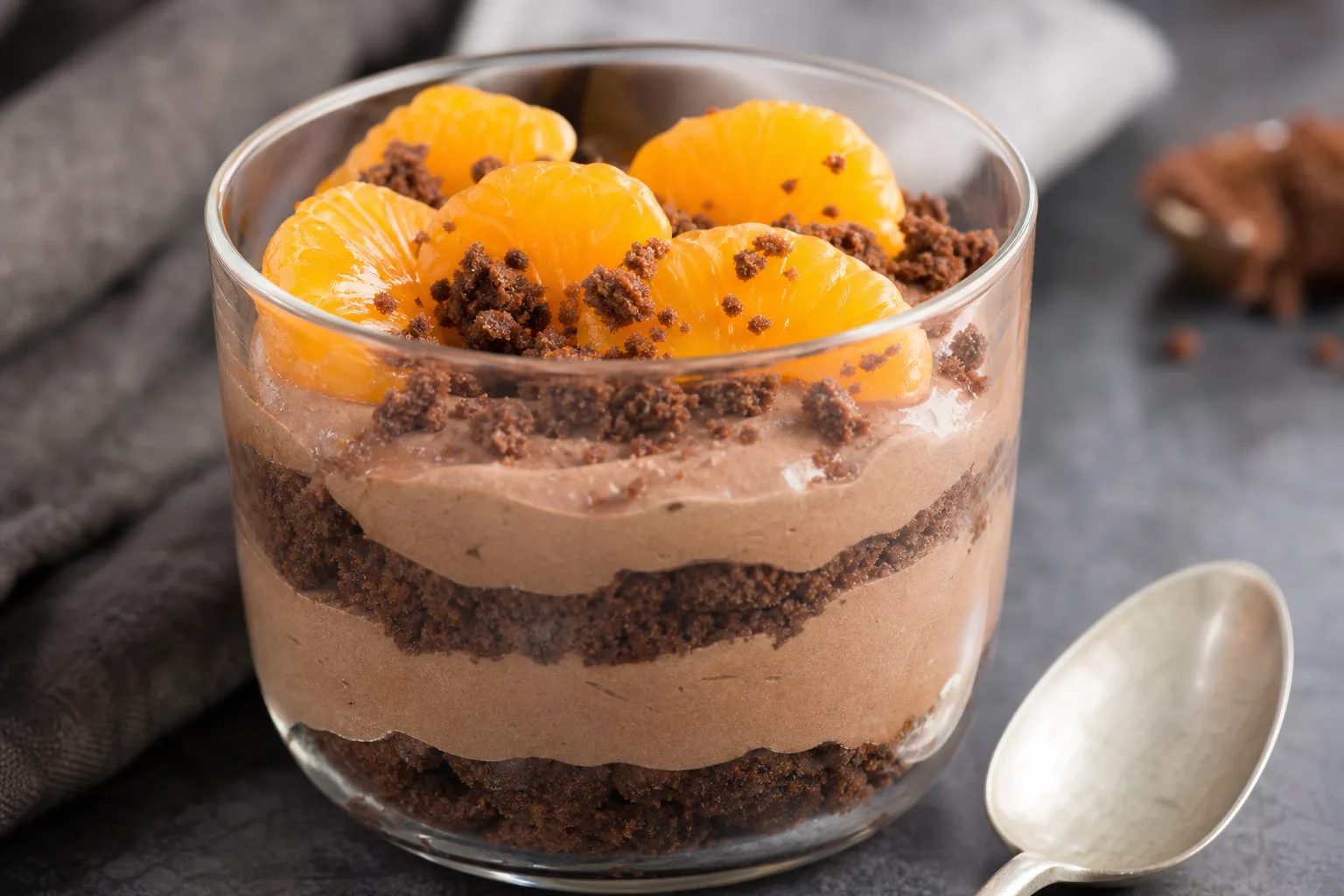 Verrine composée de biscuit au chocolat émietté, de crème chocolatée et de morceaux de mandarine sur le dessus.